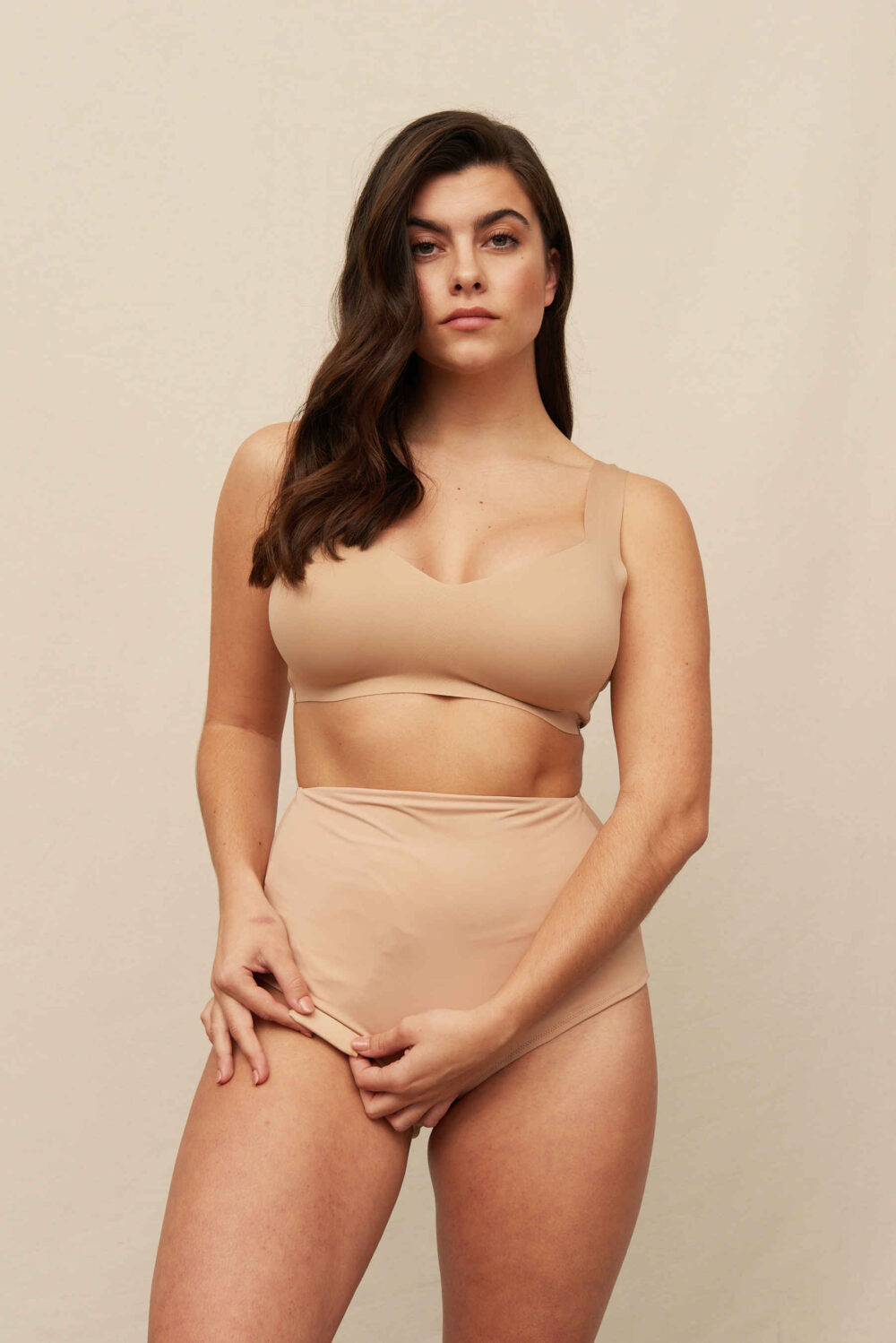 Brunette in a nude bralette and matching beige high-waist Classic ostomy panties as a pouch cover