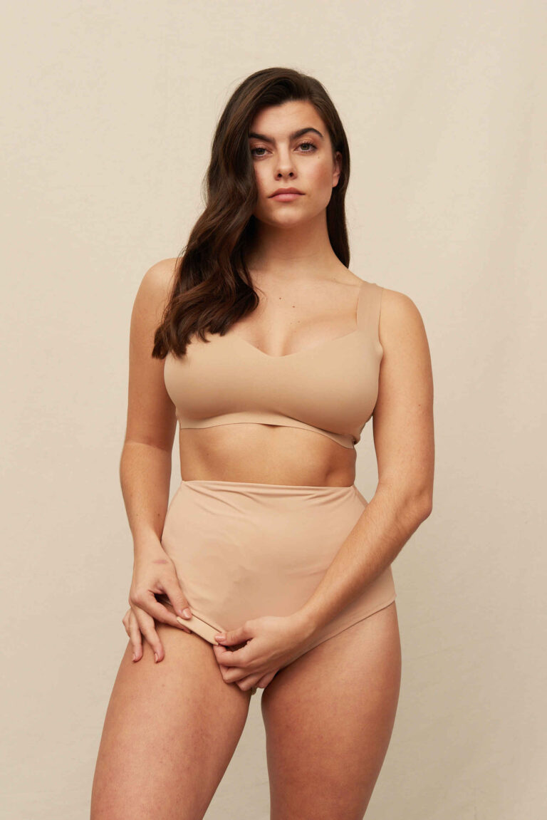Brunette in a nude bralette and matching beige high-waisted Classic knickers as an ileostomy bag cover