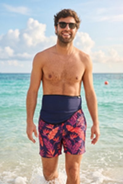 SIIL Ostomy Belt blue — man on beach in swim trunks, real ostomate
