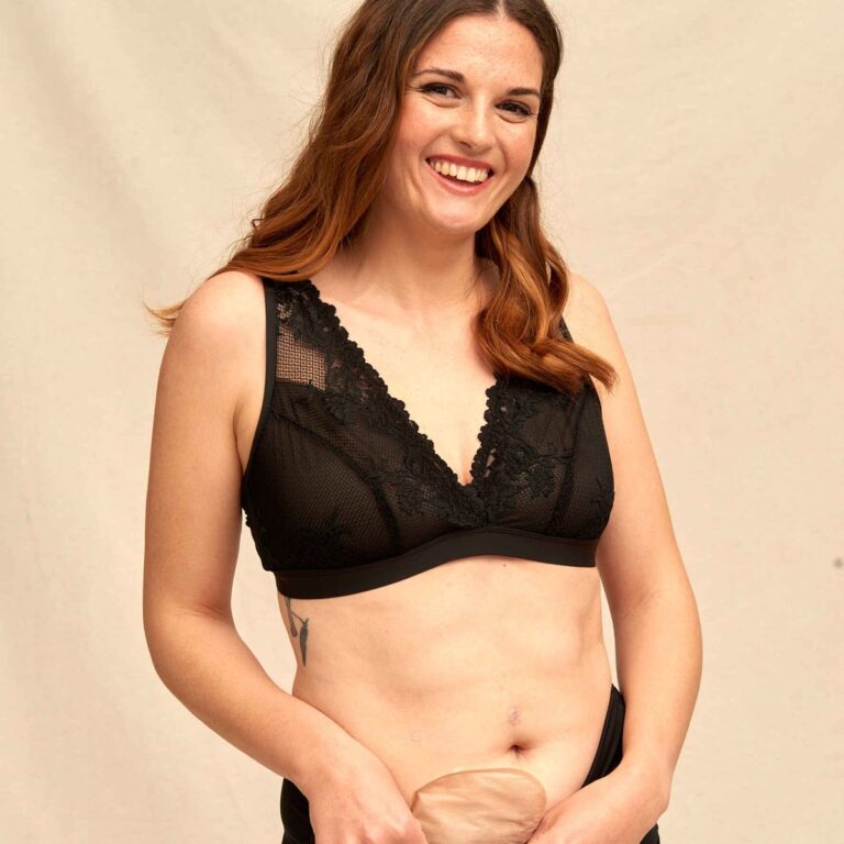 Smiling woman in black high-waisted SIIL ostomy underwear with her pouch tucked in